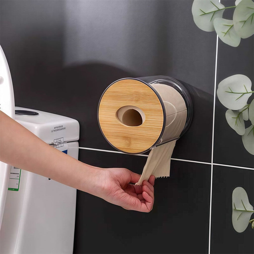 Mão puxando papel de porta papel higiênico transparente com tampa de bambu fixado na parede do banheiro.