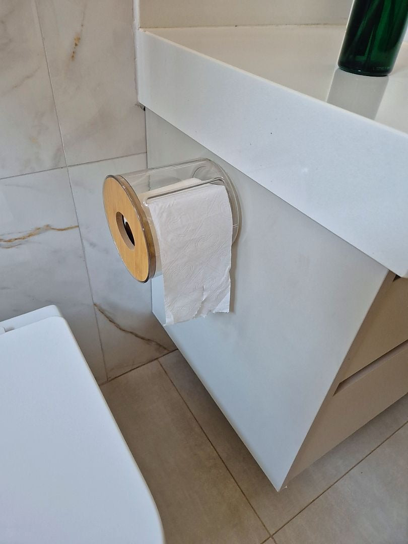 Porta papel higiênico transparente com tampa de bambu instalado na lateral de armário de banheiro.