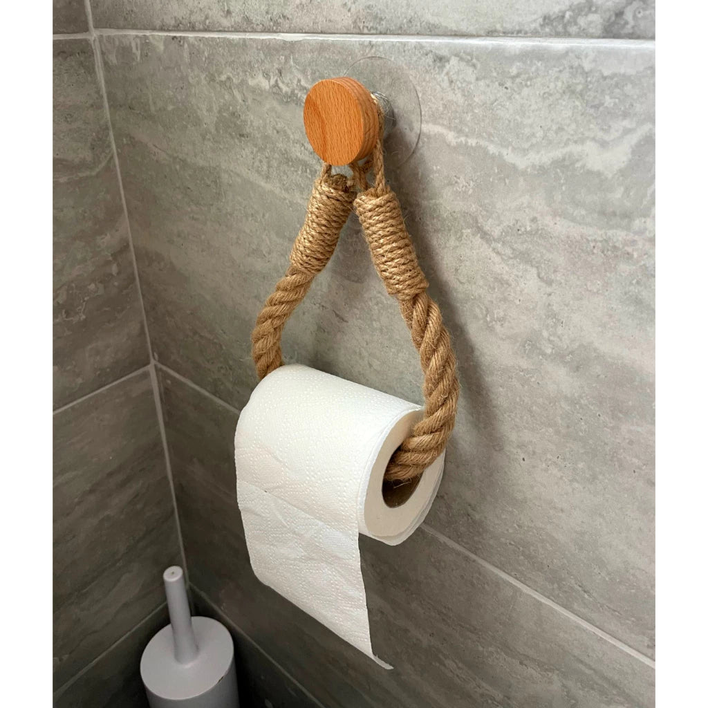 Porta papel higiênico de corda trançada com gancho de madeira instalado em azulejo cinza.
